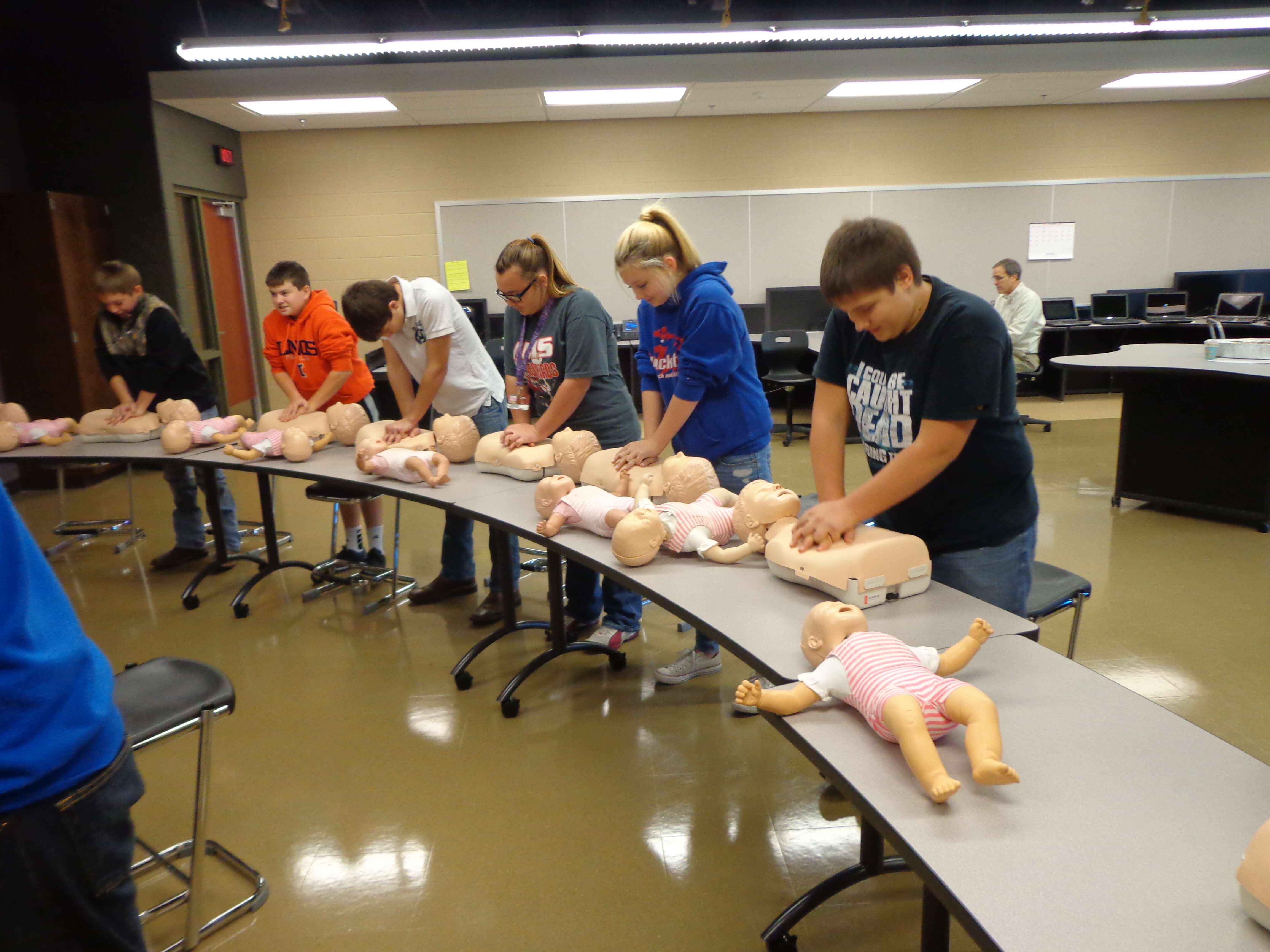 teens practicing CPR on baby dummies